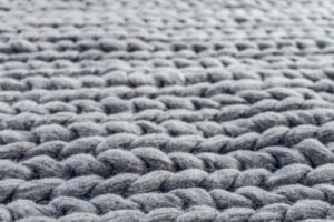 Macro photograph showing the intricate details of grey knitted wool fibers.